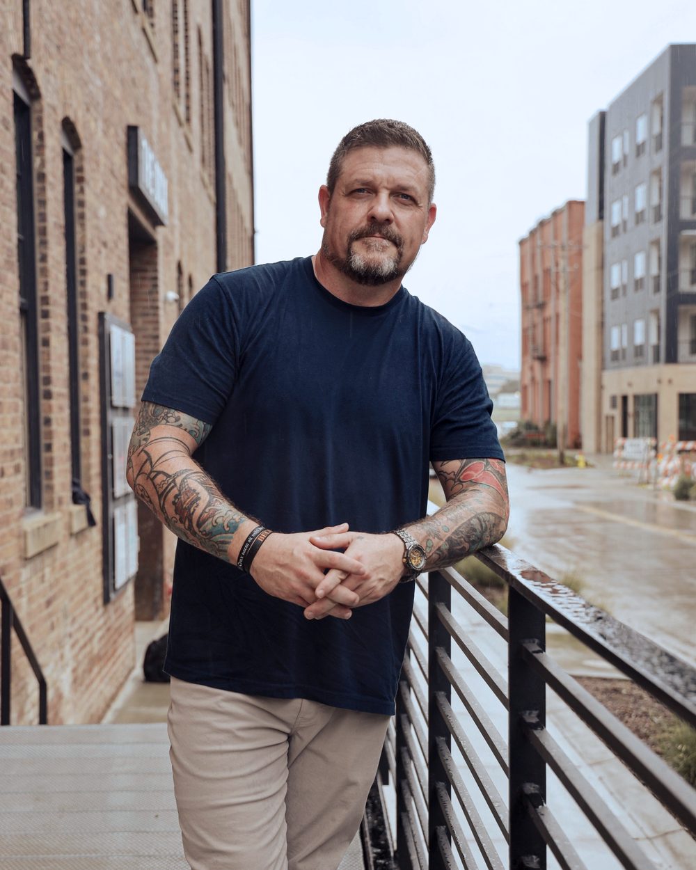 Steve Baumgartner leaning on a steel railing outside a brick industrial building